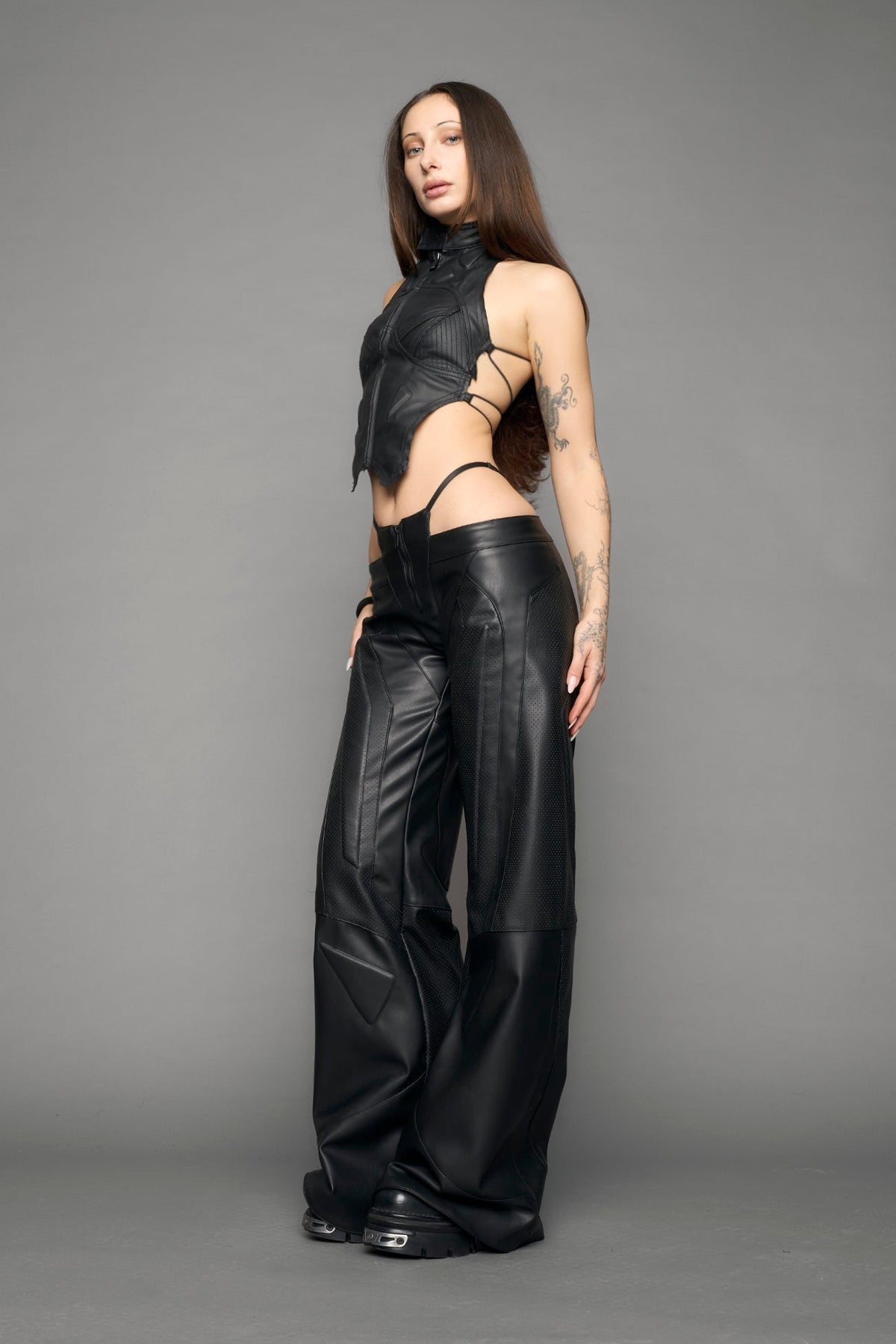 model wearing black vegan leather perforated thong pants