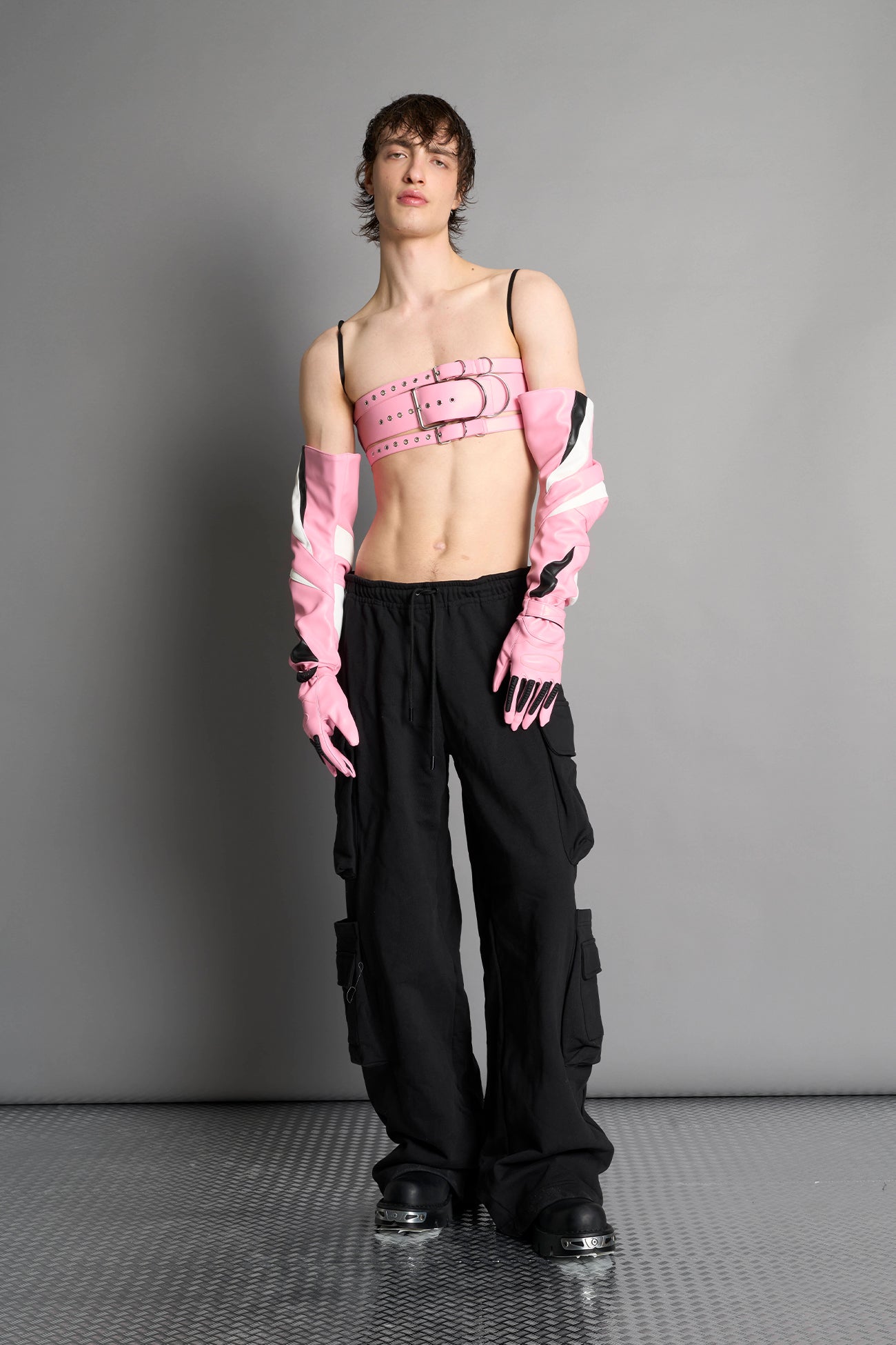 pink vegan leather belt top with three adjustable grommet straps, oversized metal buckles, and circular hardware – edgy bondage-inspired crop top for festival or clubwear.