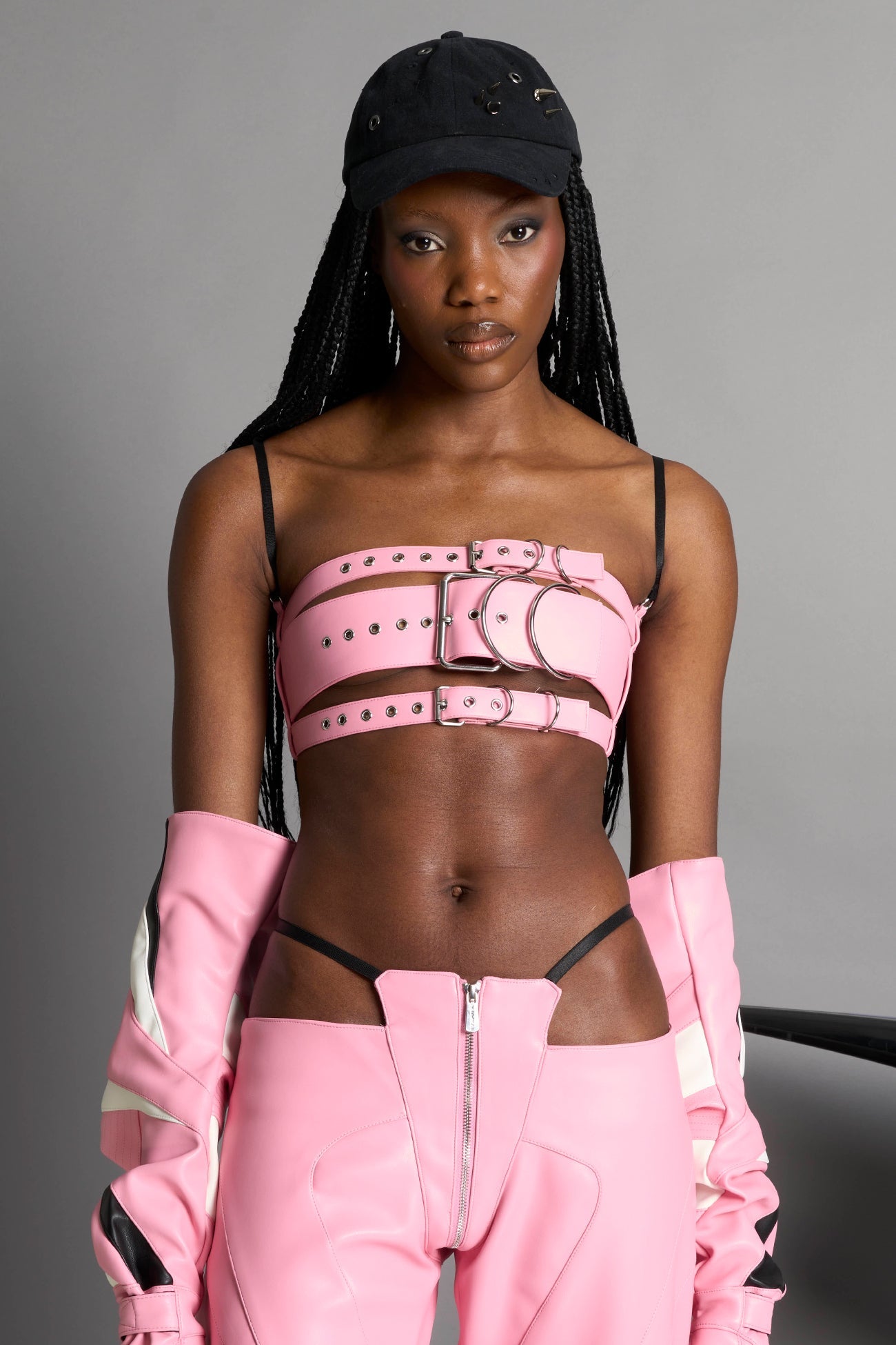 pink vegan leather belt top with three adjustable grommet straps, oversized metal buckles, and circular hardware – edgy bondage-inspired crop top for festival or clubwear.