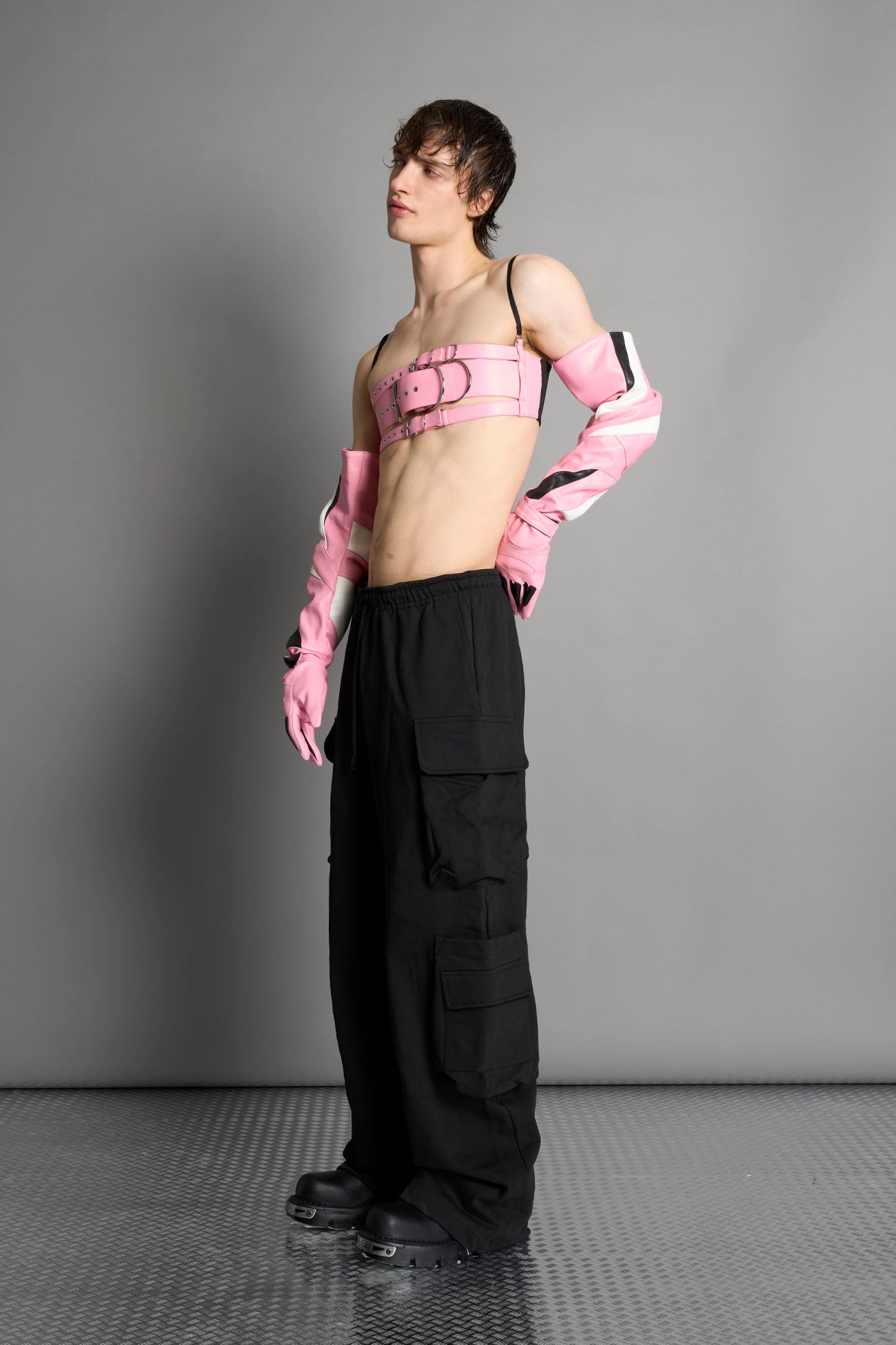 pink vegan leather belt top with three adjustable grommet straps, oversized metal buckles, and circular hardware – edgy bondage-inspired crop top for festival or clubwear.