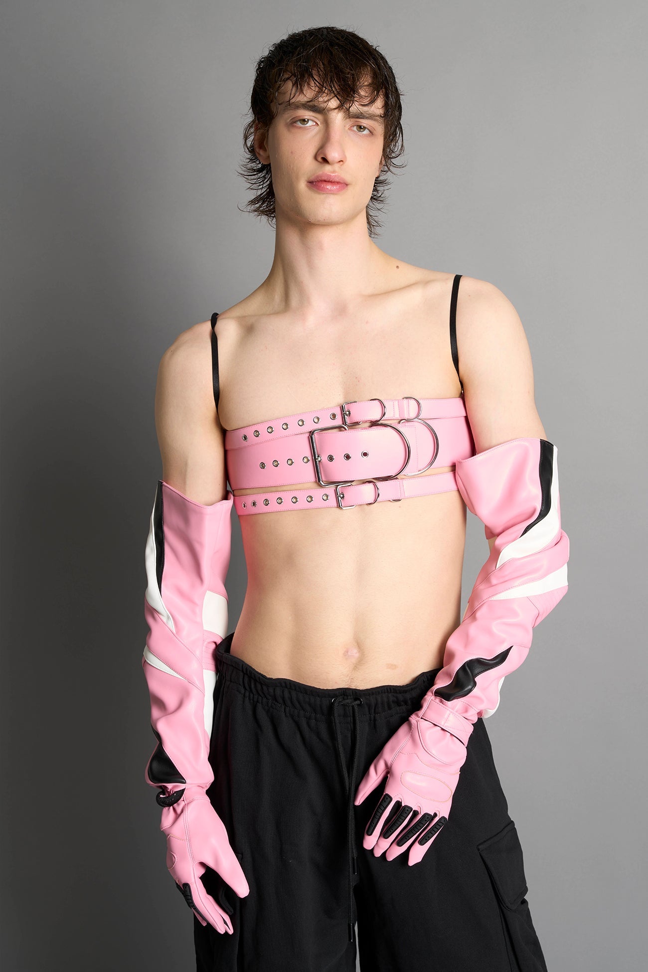 pink vegan leather belt top with three adjustable grommet straps, oversized metal buckles, and circular hardware – edgy bondage-inspired crop top for festival or clubwear.