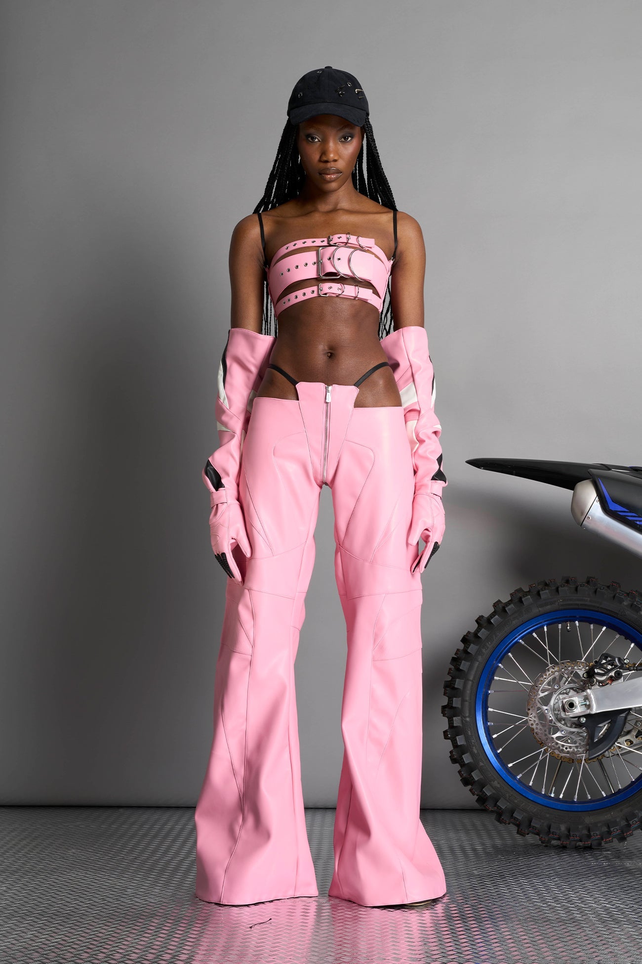 pink vegan leather belt top with three adjustable grommet straps, oversized metal buckles, and circular hardware – edgy bondage-inspired crop top for festival or clubwear.