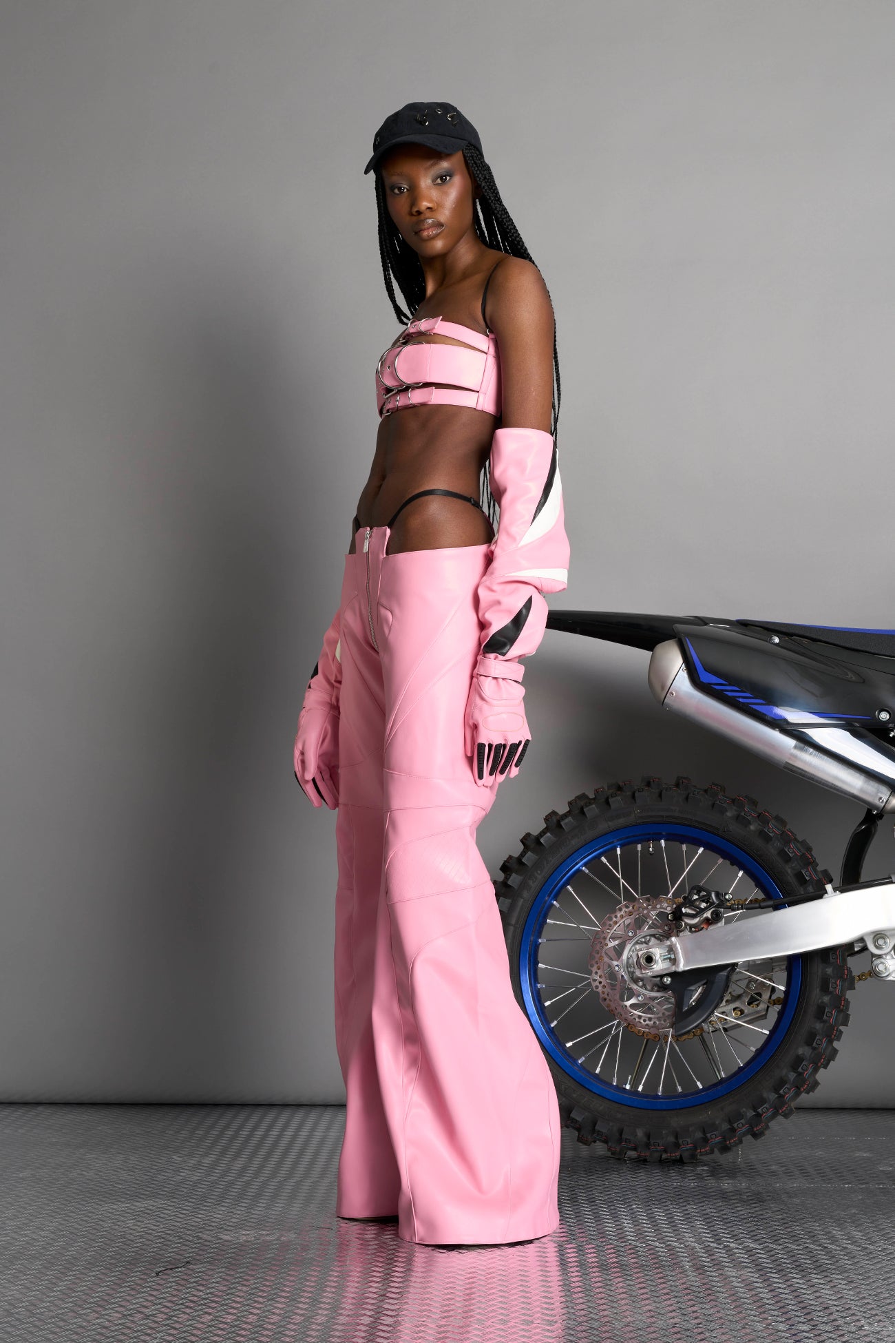 pink vegan leather belt top with three adjustable grommet straps, oversized metal buckles, and circular hardware – edgy bondage-inspired crop top for festival or clubwear.