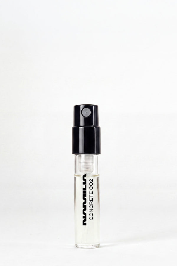 A small clear glass spray vial with a black atomizer cap, labeled 'NAMILIA CONCRETE CO2', standing upright on a white background.