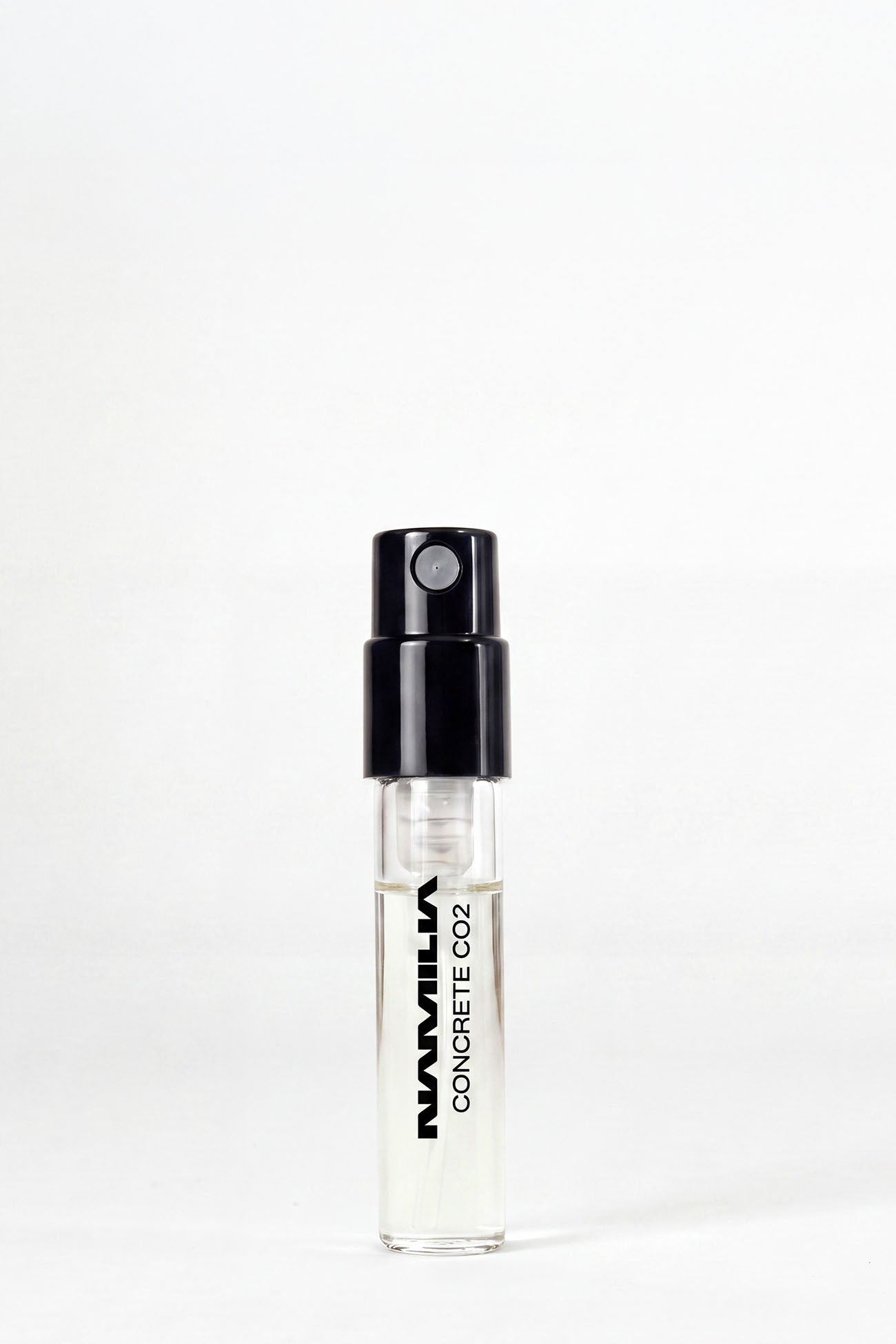 A small clear glass spray vial with a black atomizer cap, labeled 'NANVILLA CONCRETE CO2', standing upright on a white background.