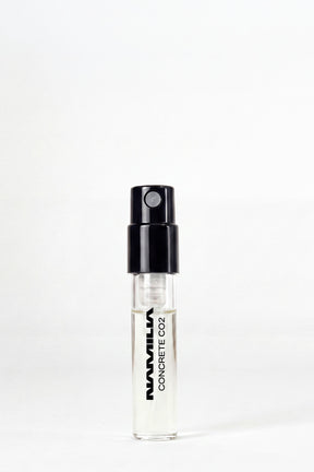 A small clear glass spray vial with a black atomizer cap, labeled 'NANVILLA CONCRETE CO2', standing upright on a white background.