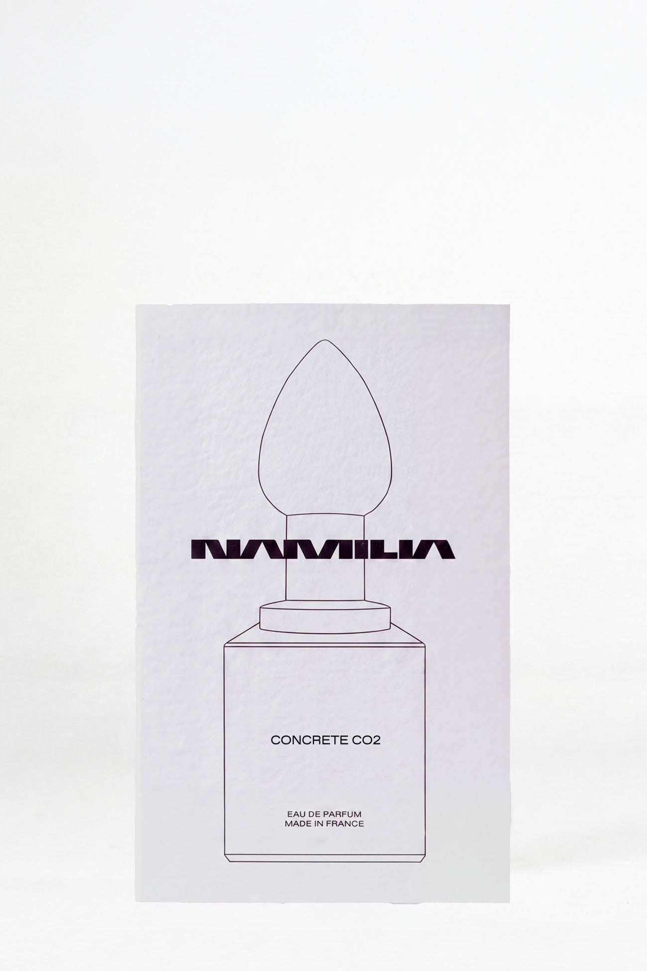 A minimalist white rectangular box for Namilia Concrete CO2 Eau de Parfum, featuring a simple black line drawing of a dropper bottle on a clean white background.