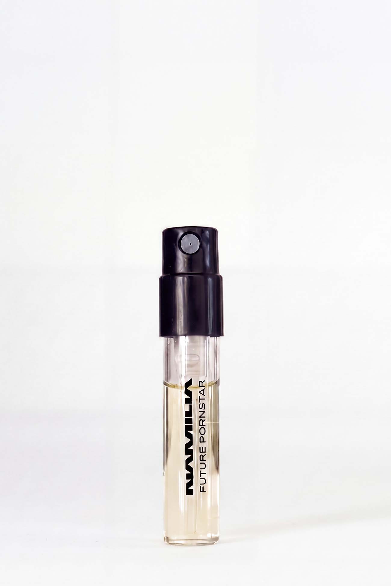 A small clear glass perfume sample vial with a black spray cap, containing a pale yellow liquid. The vial is printed with the text 'NAMILIA FUTURE PORNISTAR' in black, set against a plain white background.