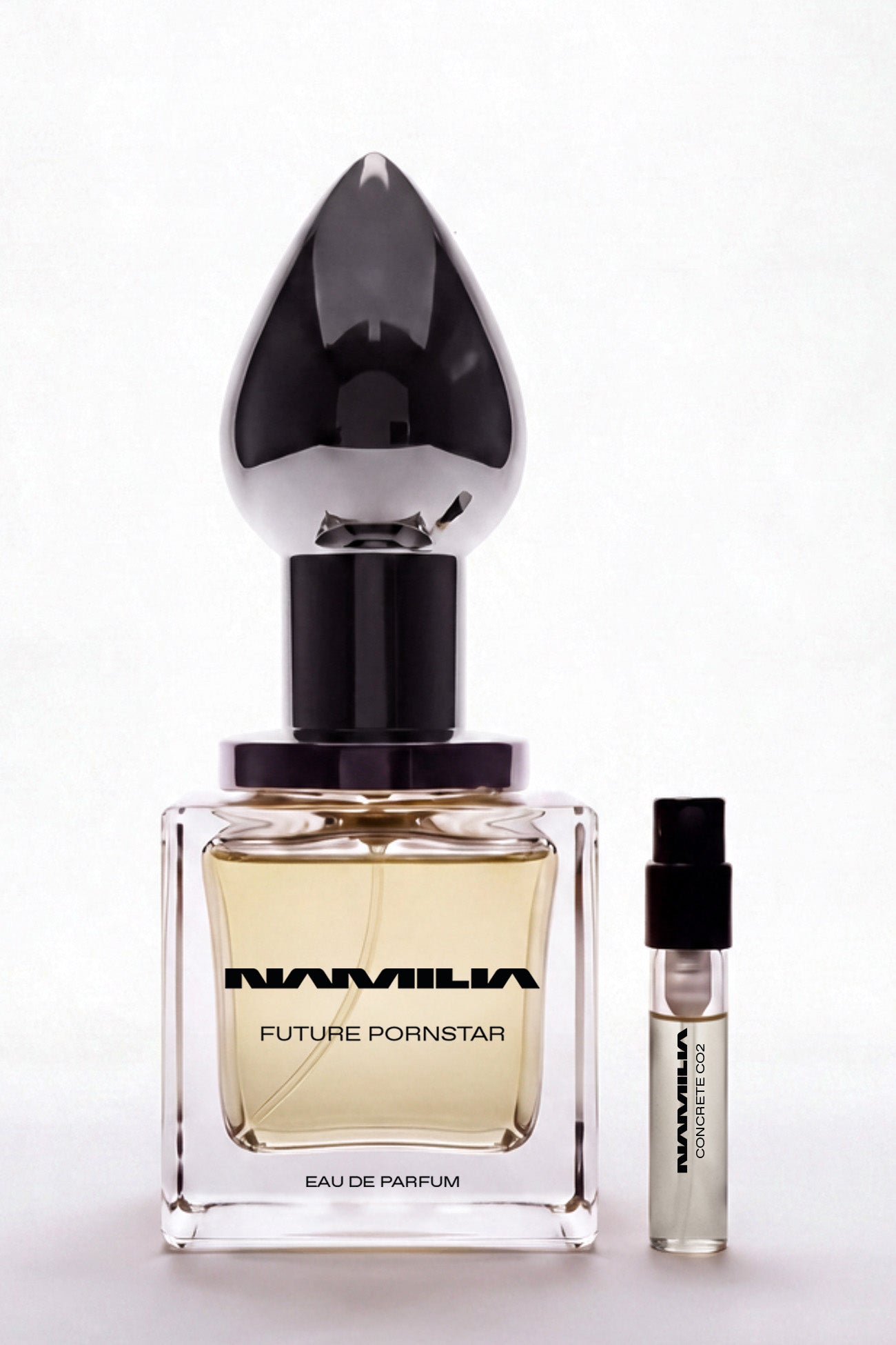 A bottle of Namila Concrete CO2 Eau de Parfum with a large reflective black teardrop-shaped cap, shown next to a small matching sample vial on a clean white background.