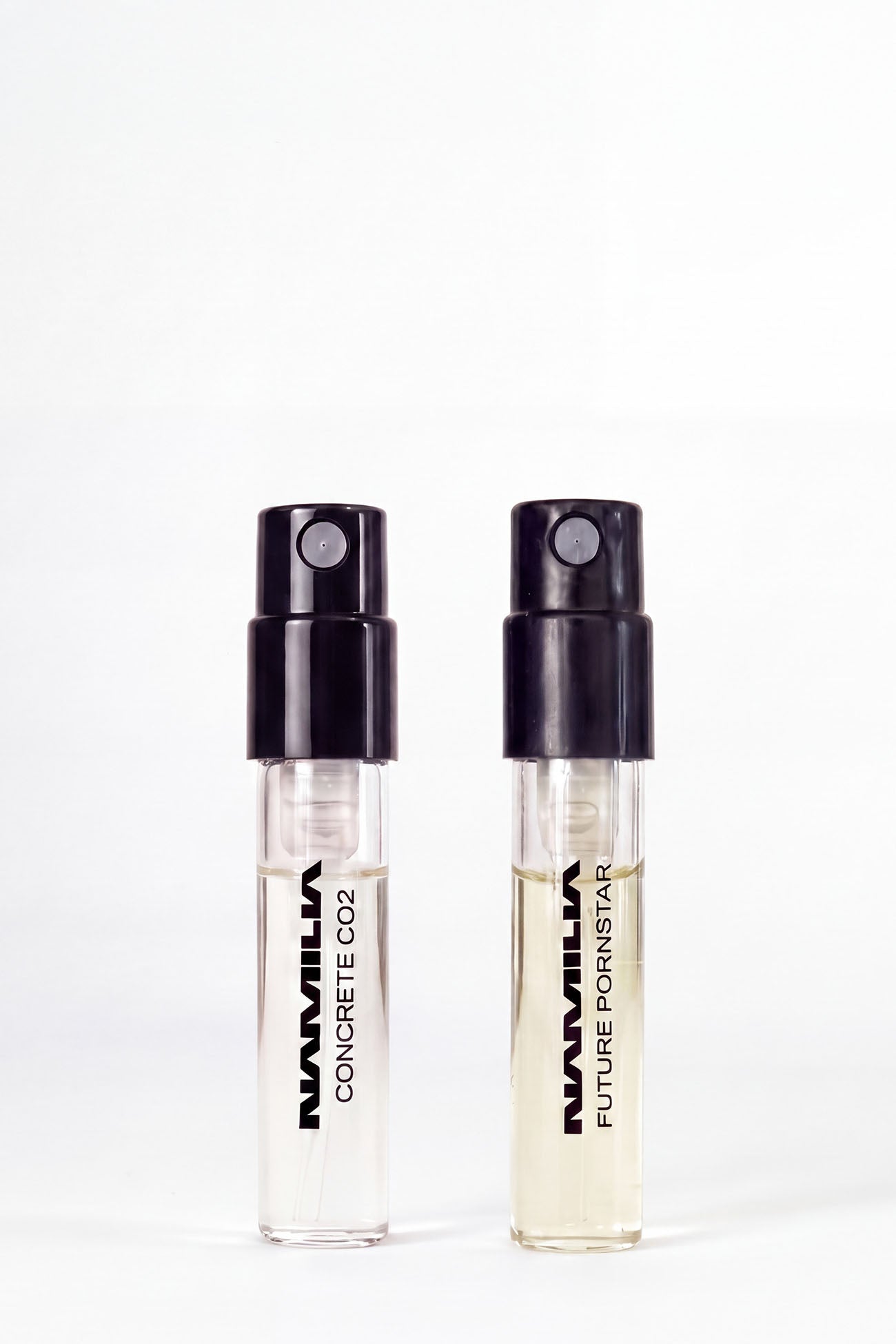 Two small parfum testers. The left vial is labeled 'NAMILIA CONCRETE CO2' and the right vial is labeled 'NAMILIA FUTURE PORNSTAR'.