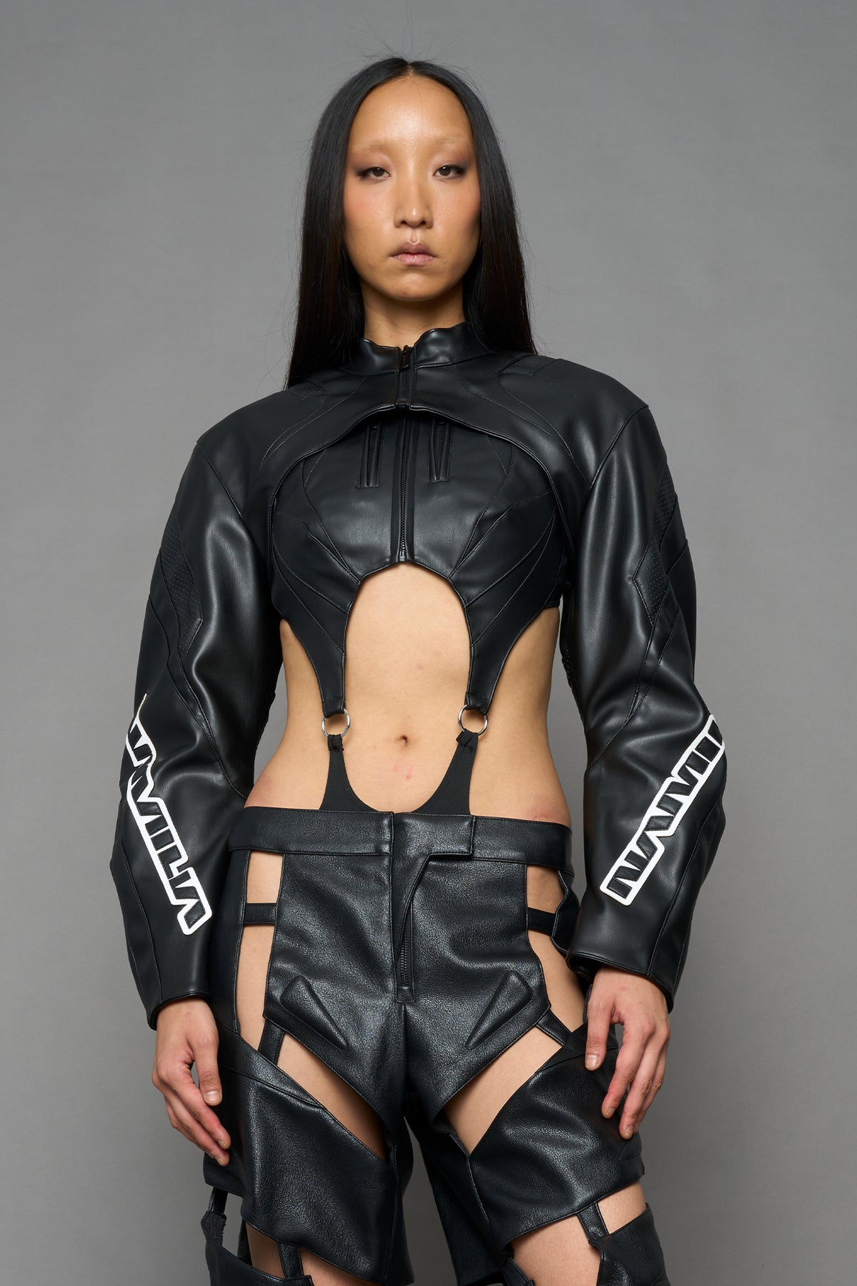 model wearing black vegan leather crop bolero jacket with  black and white logo on the arm