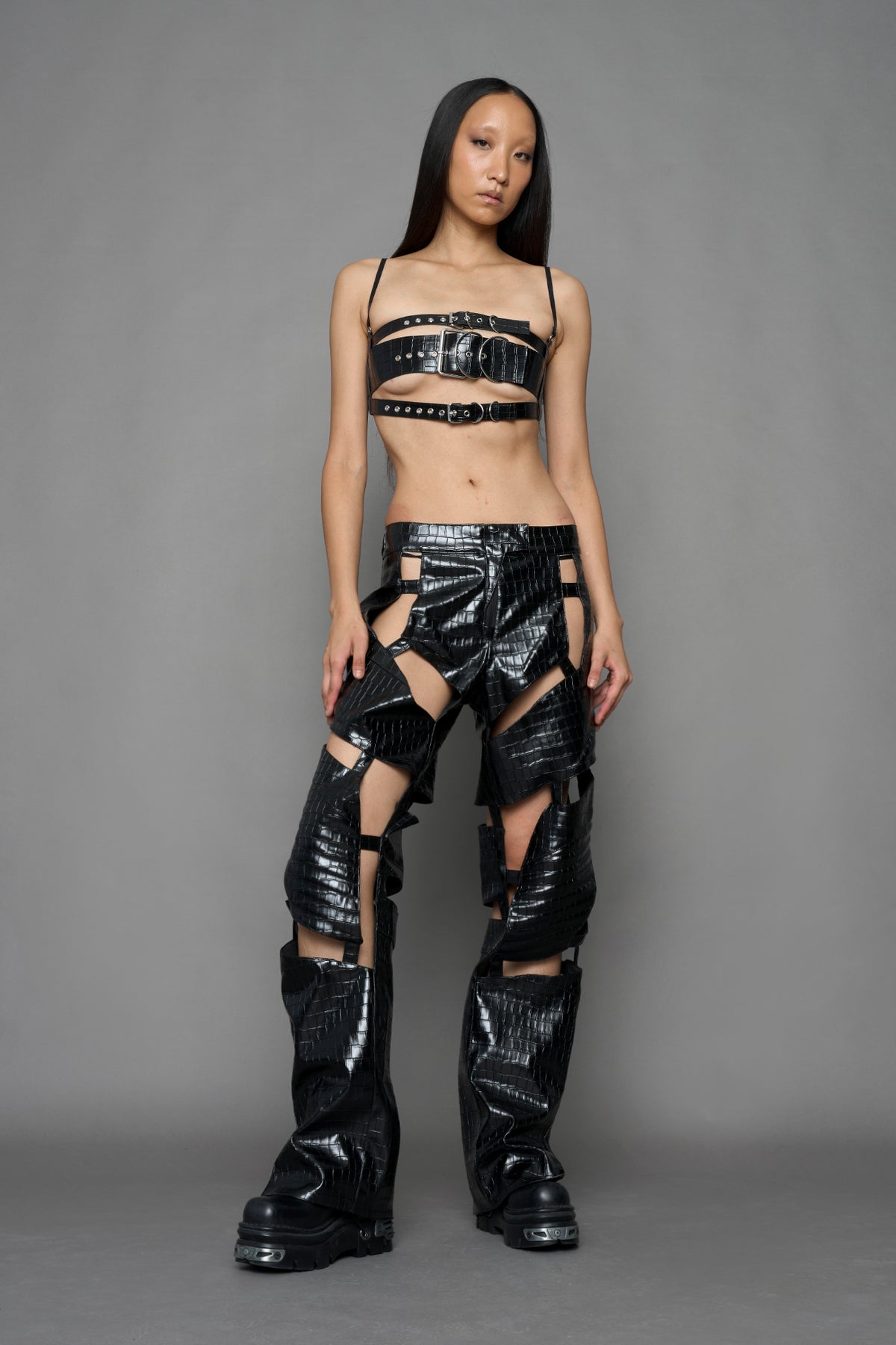 model wearing black vegan leather croc optic pants with cut outs