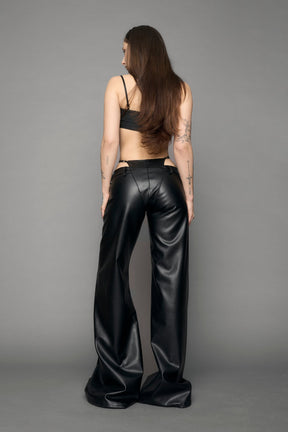 model wearing black vegan leather denim thong pants with belt detail
