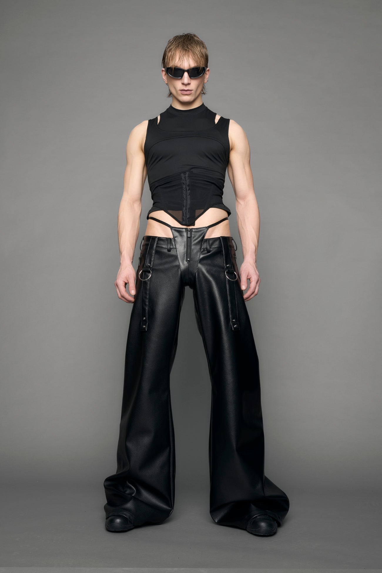 model wearing black vegan leather denim thong pants with belt detail