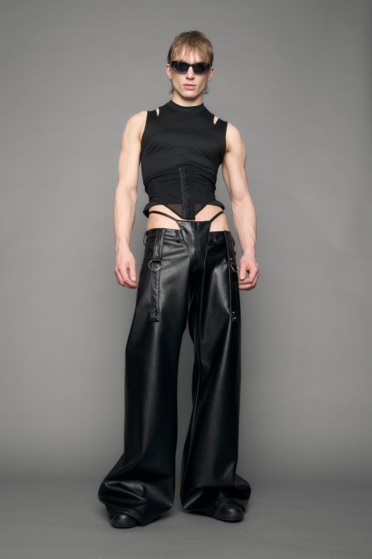 model wearing black vegan leather denim thong pants with belt detail
