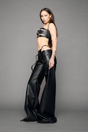 model wearing black vegan leather denim thong pants with belt detail