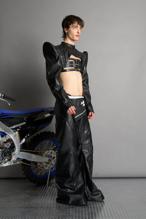Model wears the black Namilia Spike Moto Bolero Jacket with wire shoulder pads, cropped hemline, branded front zipper, motocross-style lines, and black rubber logo tag on the back.