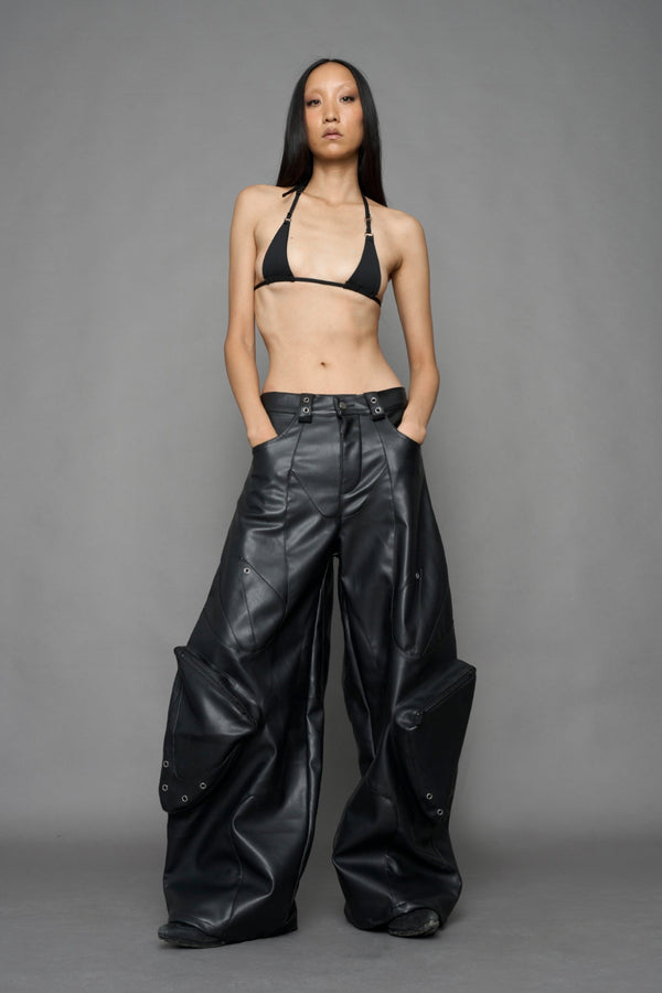 model wearing black vegan leather oversize baggy pants with pocket design details and style lines