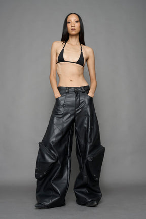 model wearing black vegan leather oversize baggy pants with pocket design details and style lines
