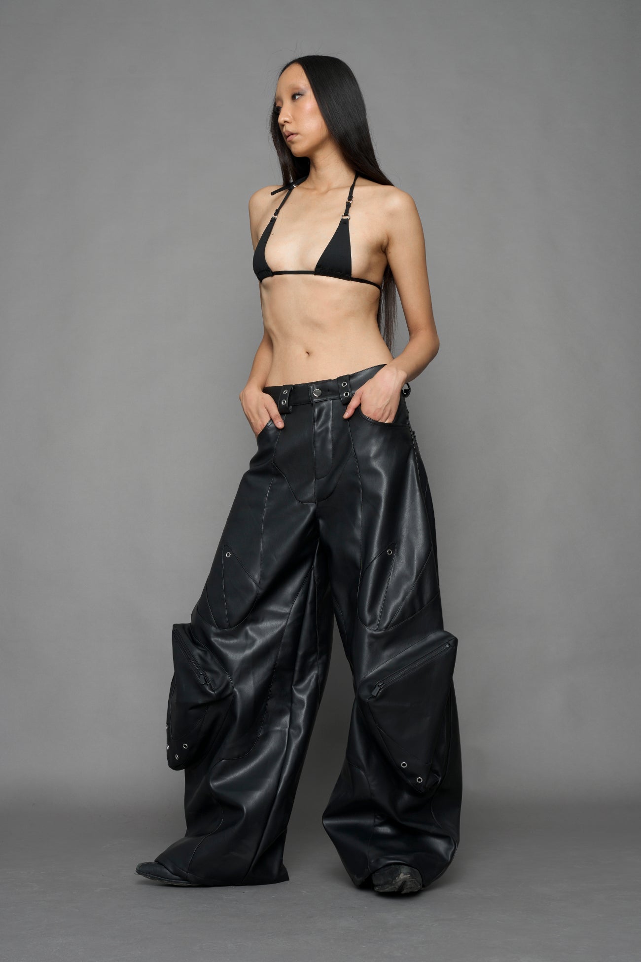 model wearing black vegan leather oversize baggy pants with pocket design details and style lines