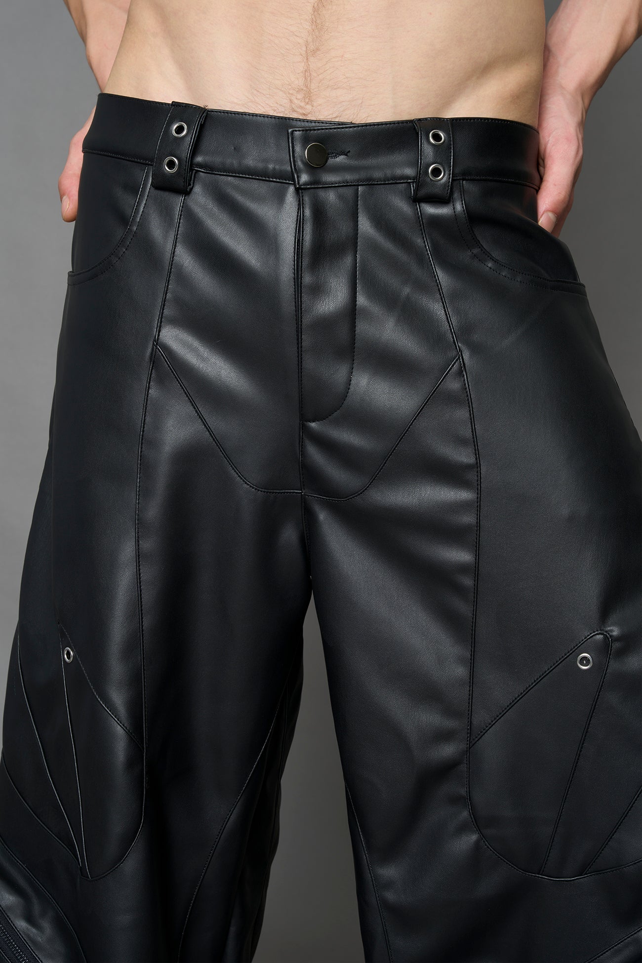 model wearing black vegan leather oversize baggy pants with pocket design details and style lines
