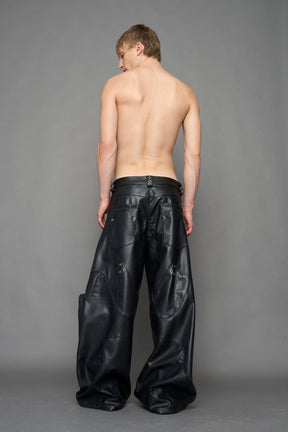 model wearing black vegan leather oversize baggy pants with pocket design details and style lines
