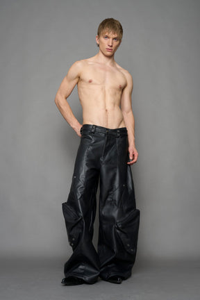 model wearing black vegan leather oversize baggy pants with pocket design details and style lines