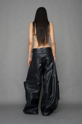 model wearing black vegan leather oversize baggy pants with pocket design details and style lines