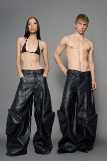 model wearing black vegan leather oversize baggy pants with pocket design details and style lines