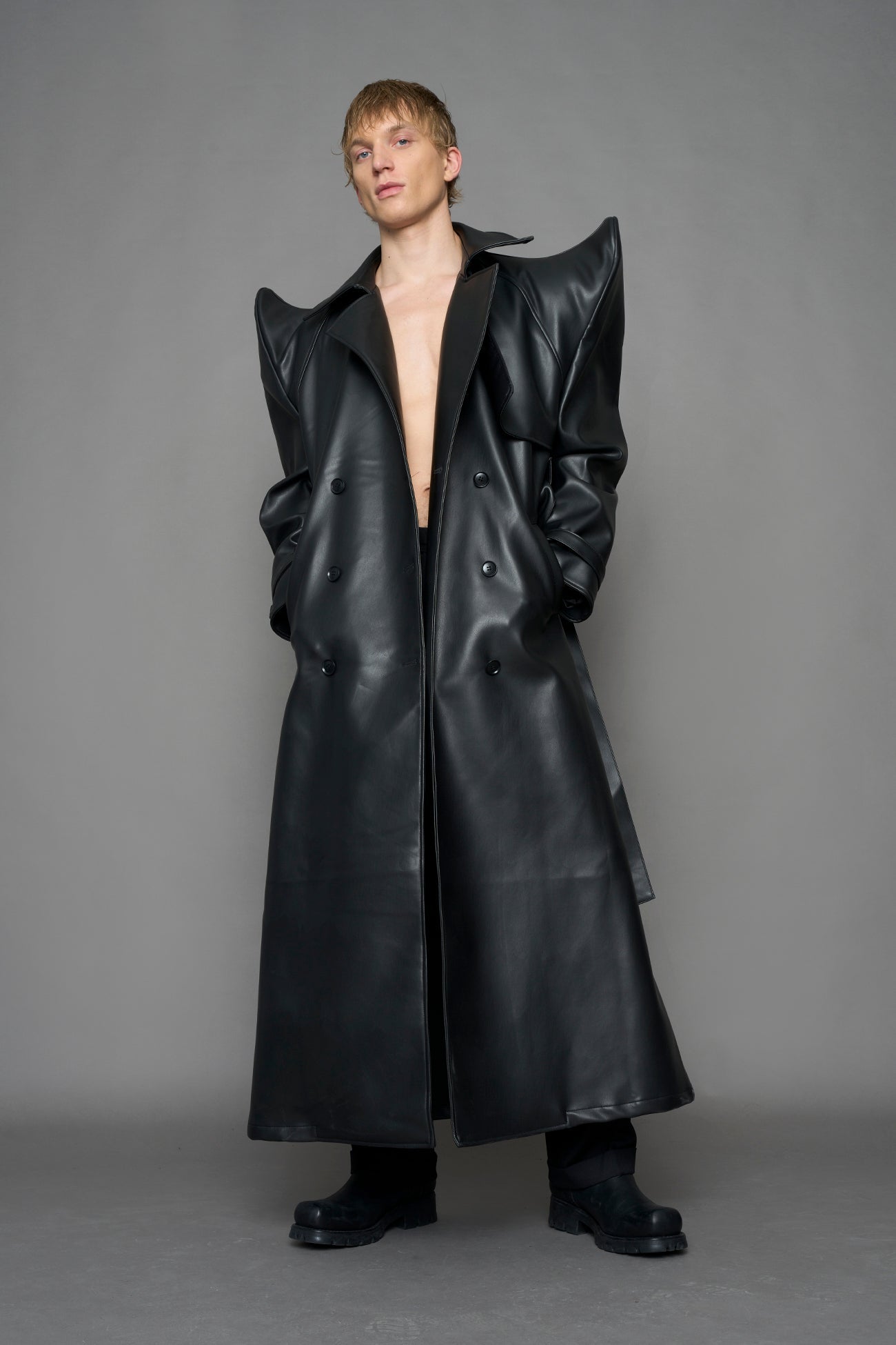 model wearing black vegan leather trench coat with sharp shoulder detail 