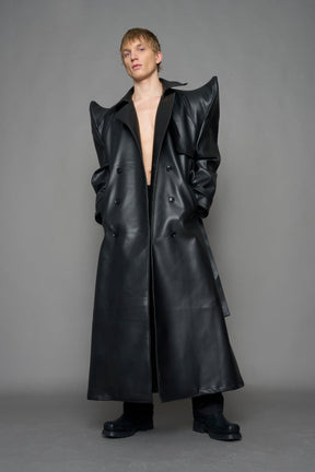 model wearing black vegan leather trench coat with sharp shoulder detail 