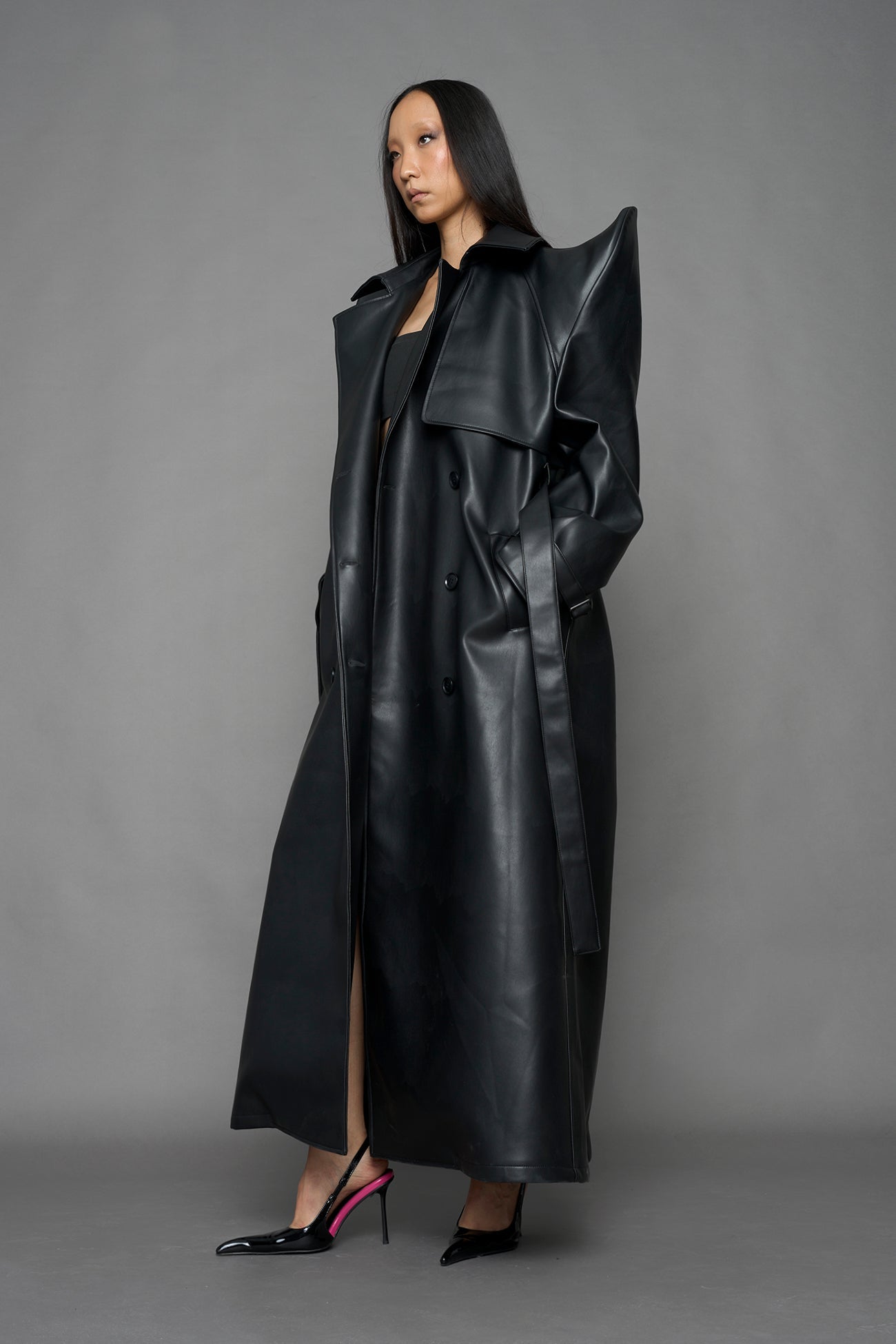 model wearing black vegan leather trench coat with sharp shoulder detail 