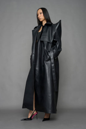 model wearing black vegan leather trench coat with sharp shoulder detail 