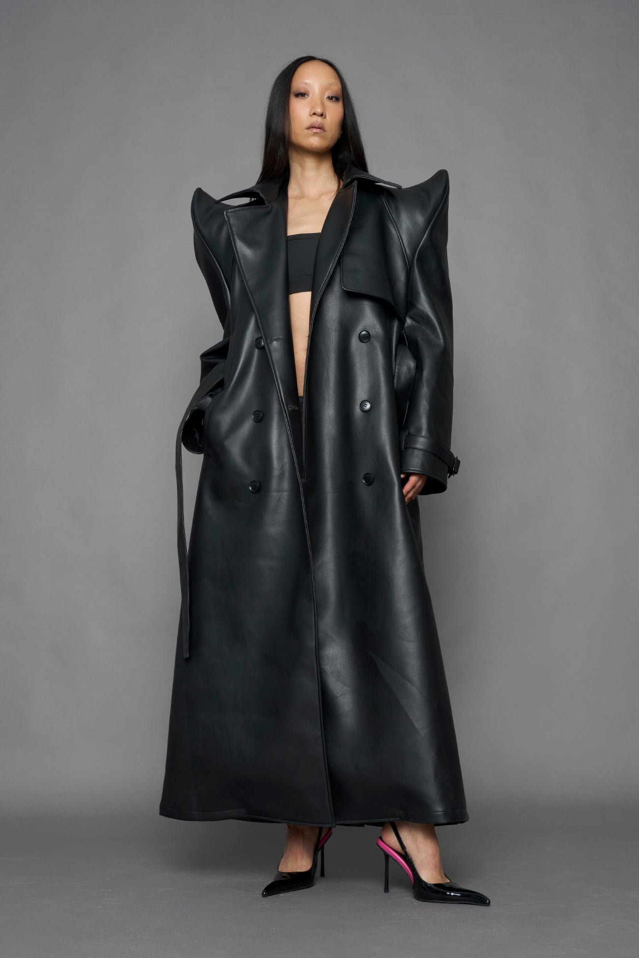 model wearing black vegan leather trench coat with sharp shoulder detail 