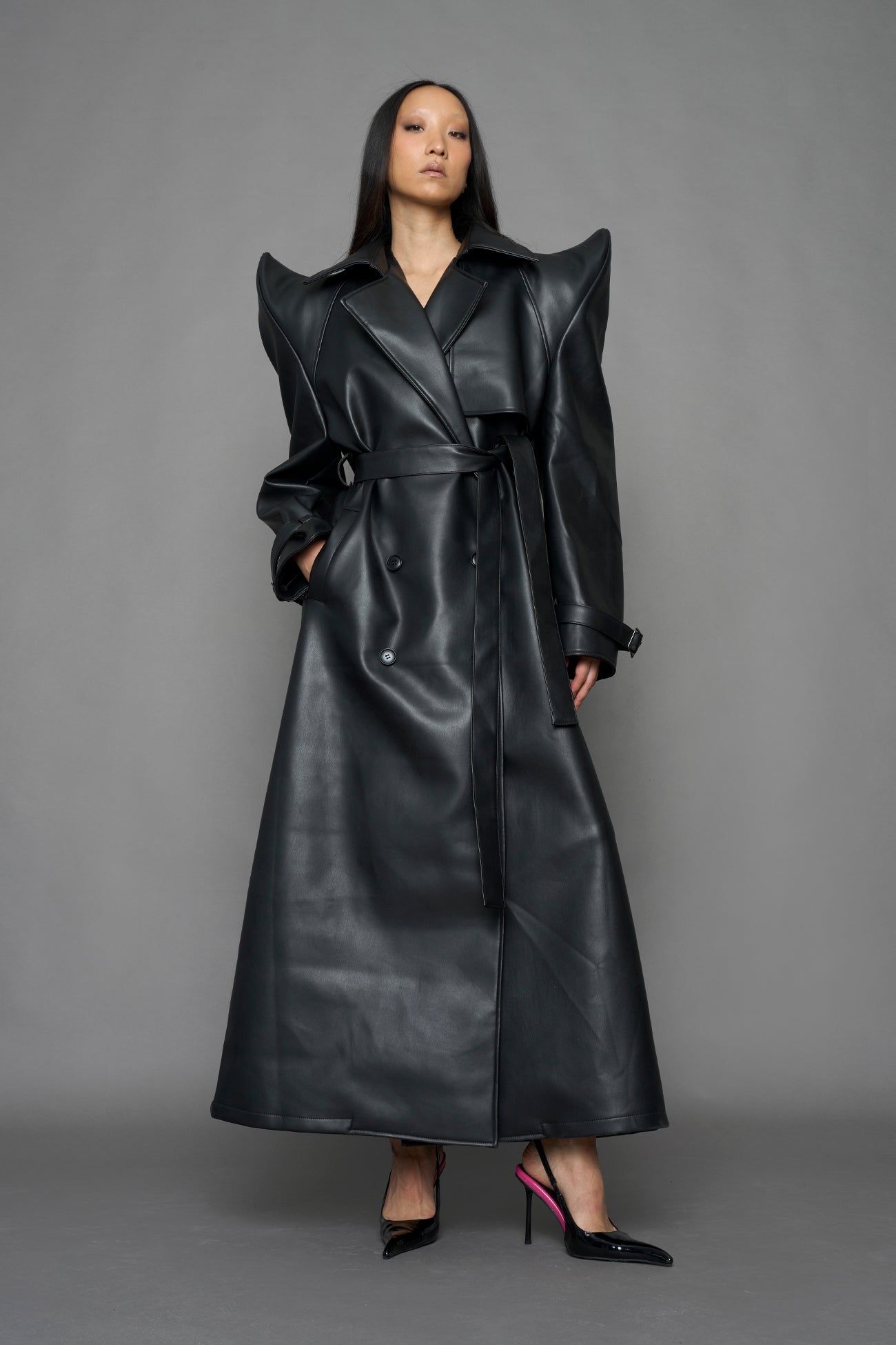 model wearing black vegan leather trench coat with sharp shoulder detail 