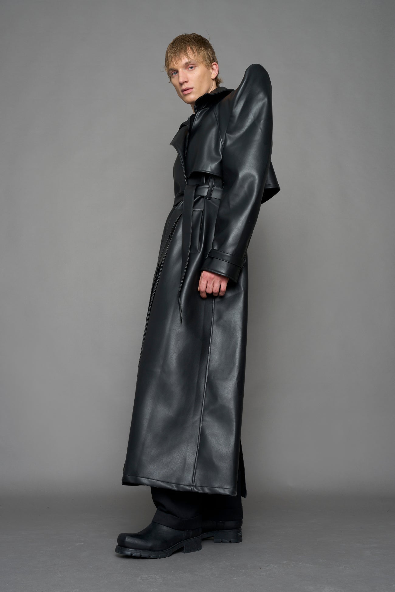 model wearing black vegan leather trench coat with sharp shoulder detail 