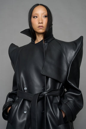 model wearing black vegan leather trench coat with sharp shoulder detail 