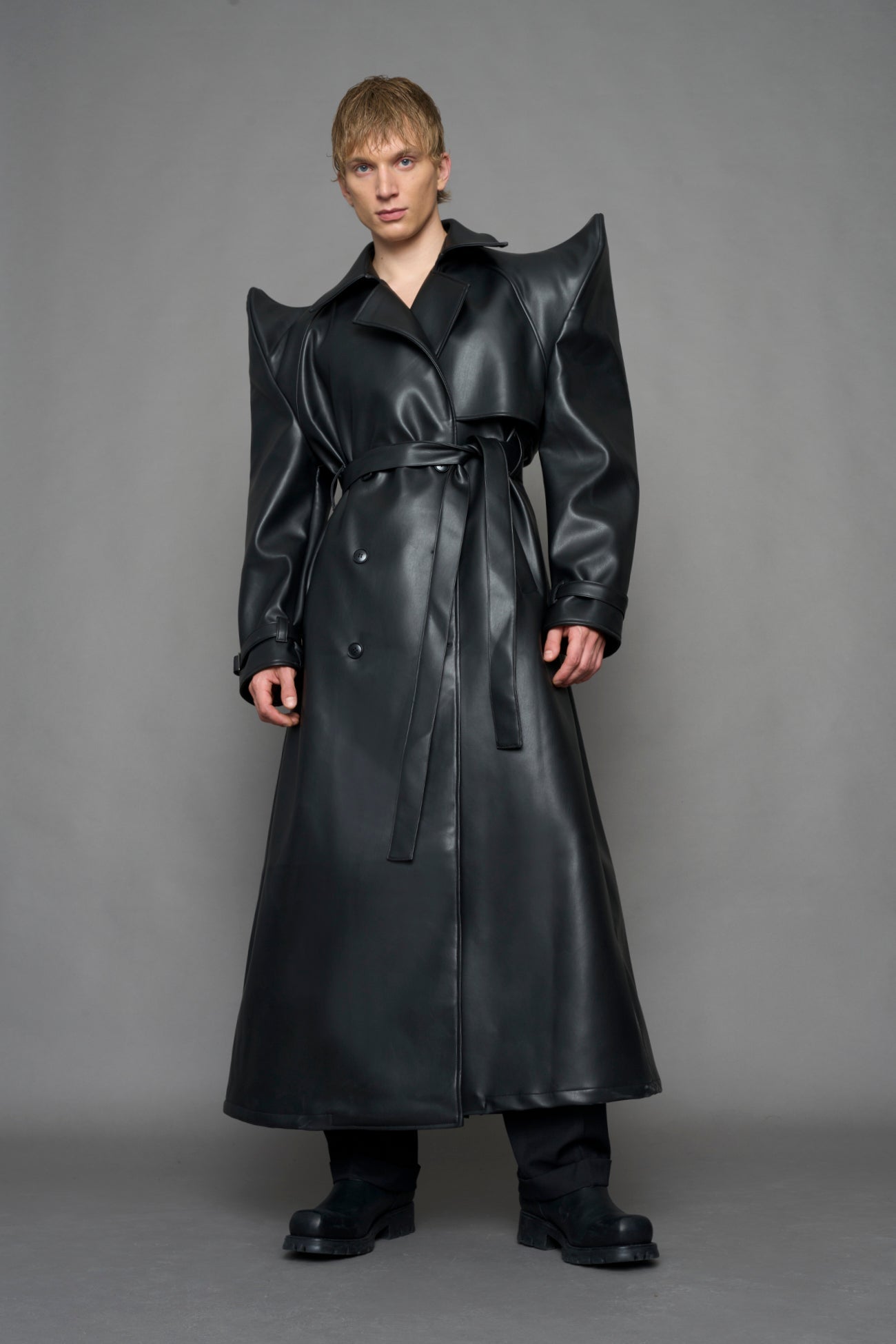 model wearing black vegan leather trench coat with sharp shoulder detail 