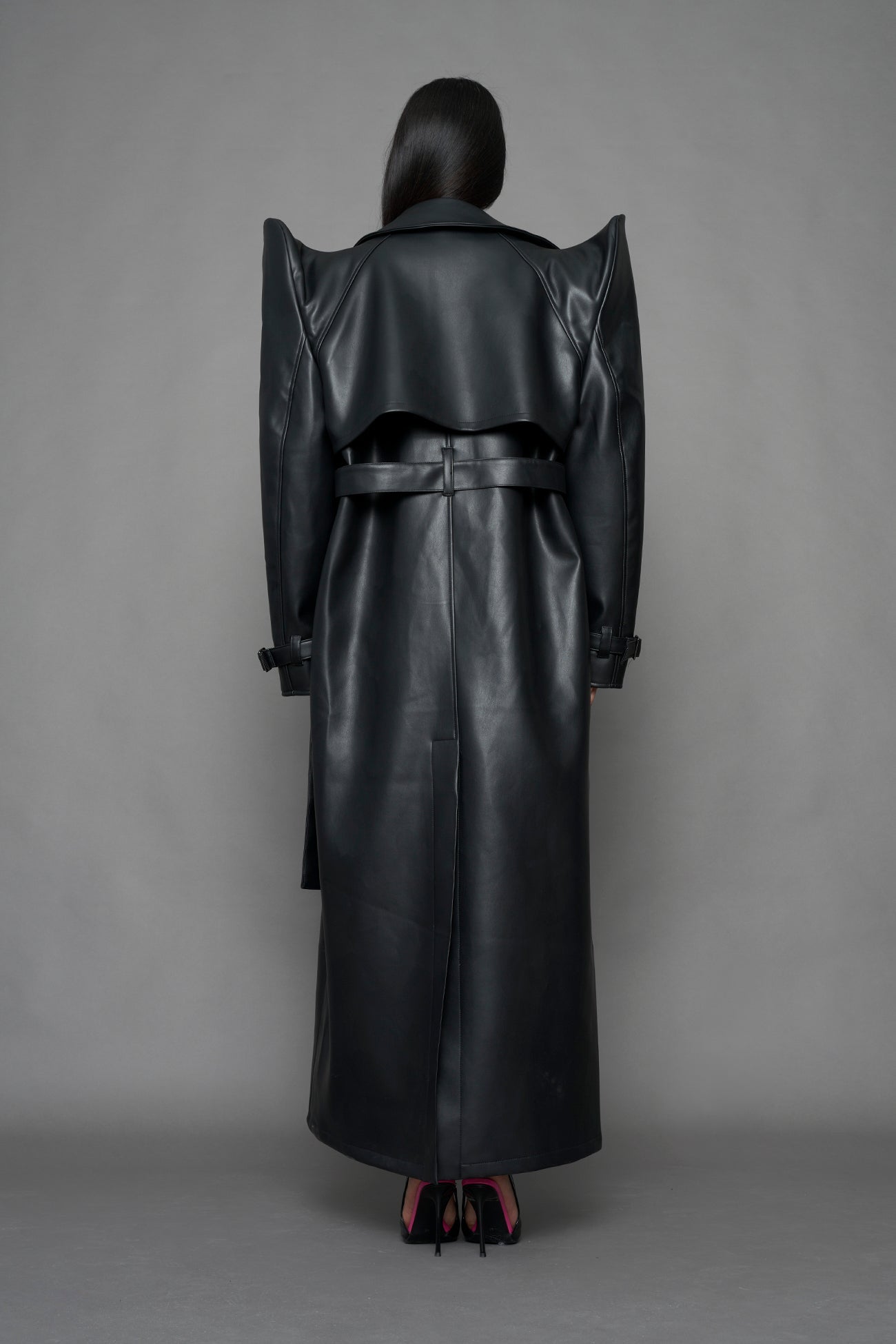 model wearing black vegan leather trench coat with sharp shoulder detail 