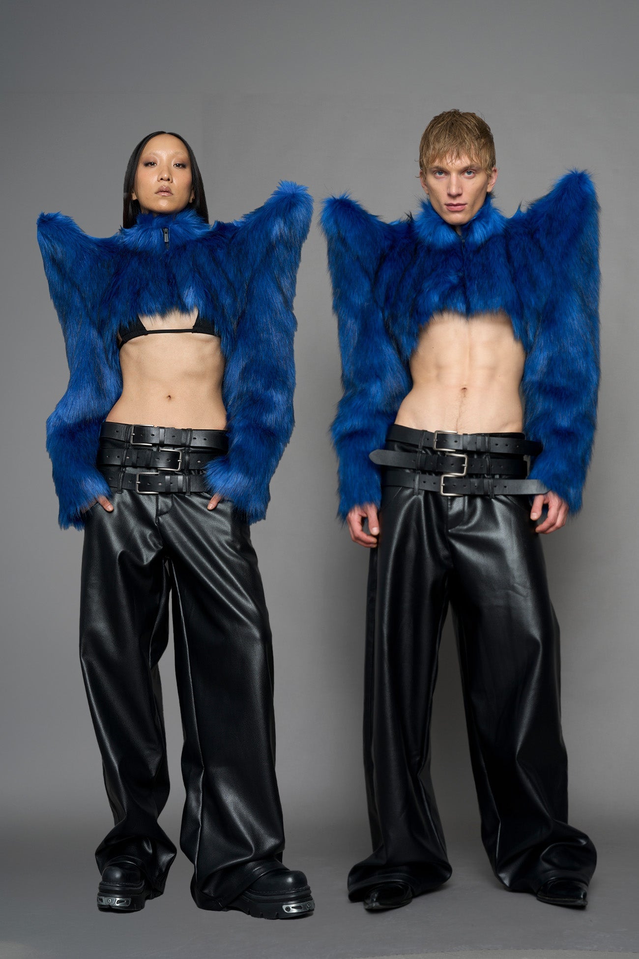model wearing blue faux fur crop jacket with sharp shoulder design and black pants