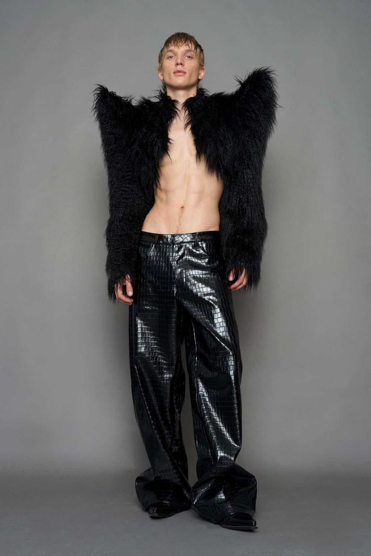 model wearing black faux fur crop jacket with sharp shoulder design and black pants