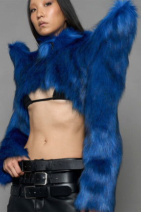 model wearing blue faux fur crop jacket with sharp shoulder design and black pants