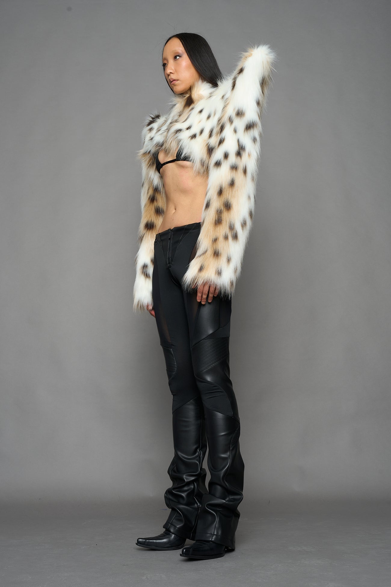 model wearing beige faux fur crop jacket with sharp shoulder design and black pants