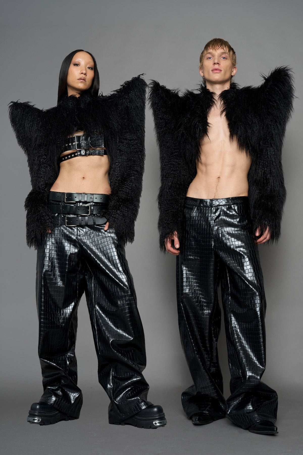 model wearing black faux fur crop jacket with sharp shoulder design and black pants