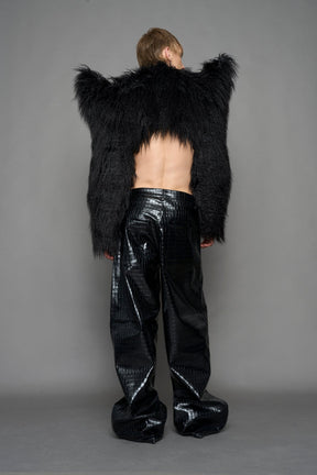 model wearing black faux fur crop jacket with sharp shoulder design and black pants