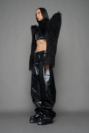model wearing black faux fur crop jacket with sharp shoulder design and black pants