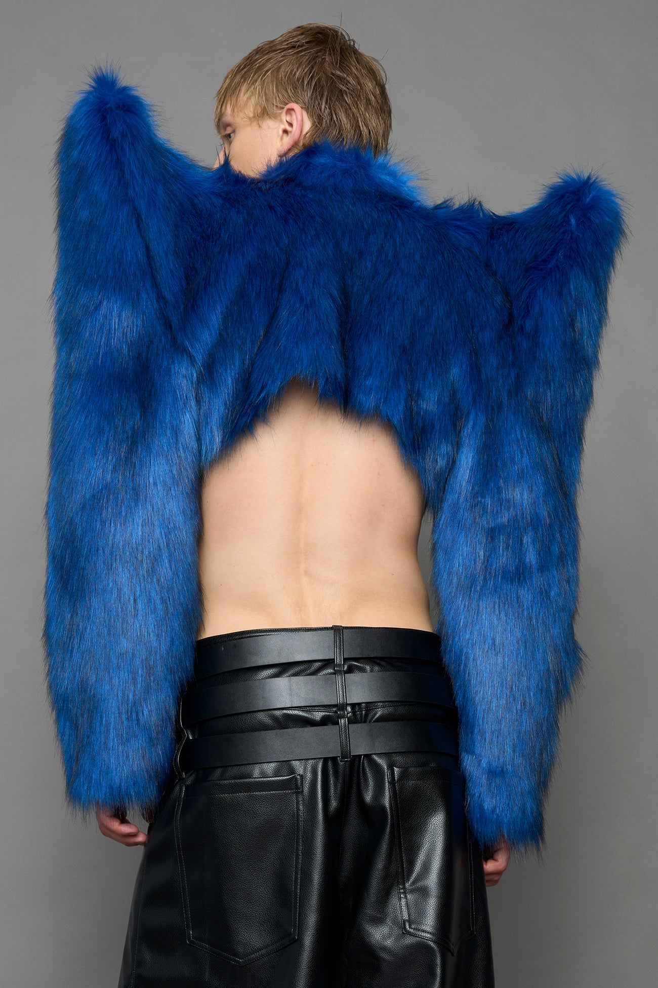 model wearing blue faux fur crop jacket with sharp shoulder design and black pants