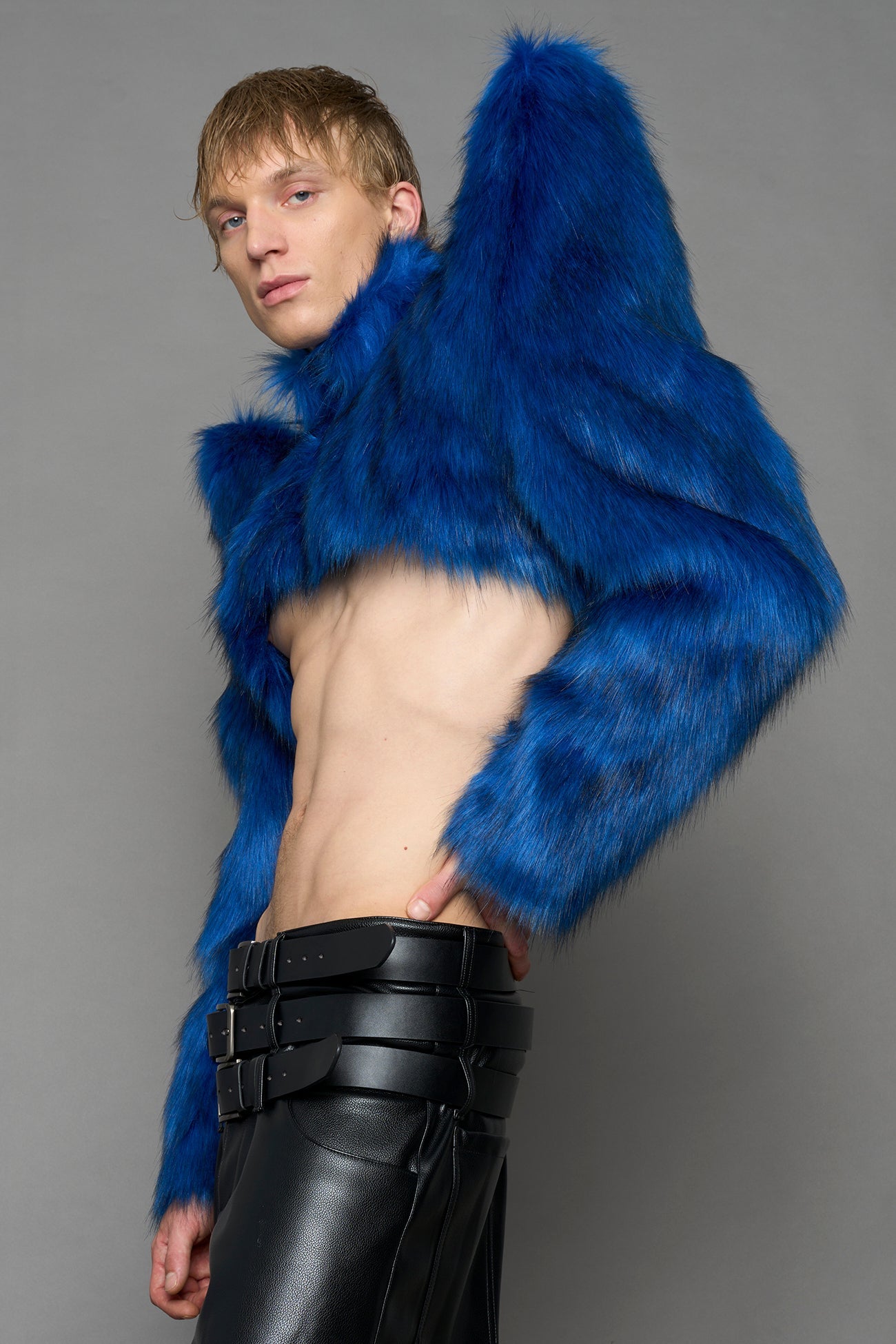 model wearing blue faux fur crop jacket with sharp shoulder design and black pants