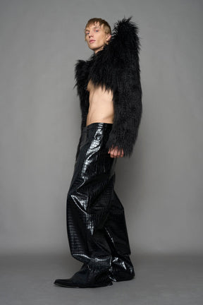 model wearing black faux fur crop jacket with sharp shoulder design and black pants
