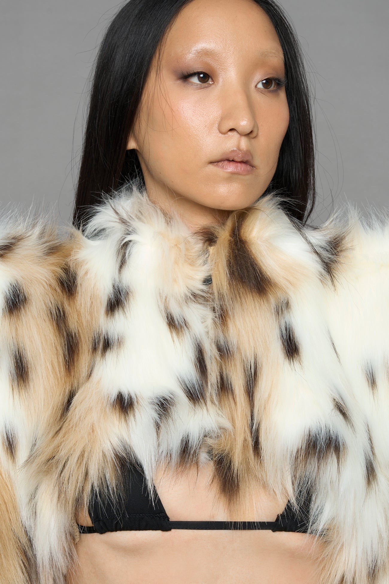 model wearing beige faux fur crop jacket with sharp shoulder design and black pants